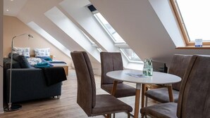 Une chambre de style loft moderne, dotée d’une lucarne, d’un canapé et d’un coin repas avec des chaises.