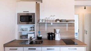 Une cuisine moderne dotée d’un four à micro-ondes encastré, d’un évier en acier inoxydable et d’un plan de travail en bois.
