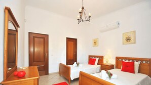 A hotel room with two beds, a wooden dresser, a red rug, and a chandelier. - Quiet retreat with pool and BBQ (Albufeira)
