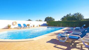 A swimming pool with lounge chairs and potted plants.