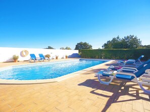 A swimming pool with lounge chairs and potted plants.