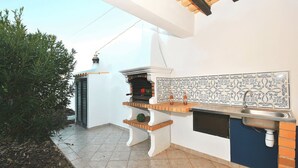 An outdoor kitchen with a built-in grill, a sink, and decorative tiles. - Quiet retreat with pool and BBQ (Albufeira)