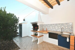 An outdoor kitchen with a built-in grill, a sink, and decorative tiles. - Quiet retreat with pool and BBQ (Albufeira)