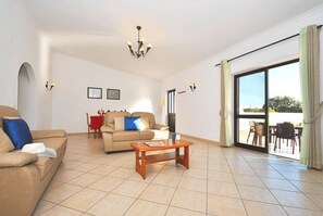 A spacious living room with a sofa, a coffee table, and a dining area with a table and chairs.