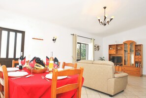Comedor con mantel rojo, sillas de madera y mesa de vidrio dispuesta para una comida.