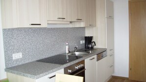 A kitchen with light wood cabinets, a granite countertop, a coffee maker, and a dishwasher. - Holidays at the Fam. Moosbrugger volgo Rainzhof (Aich)