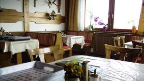 A dining area with wooden tables and chairs, a white tablecloth, and a vase with flowers. - Holidays at the Fam. Moosbrugger volgo Rainzhof (Aich)