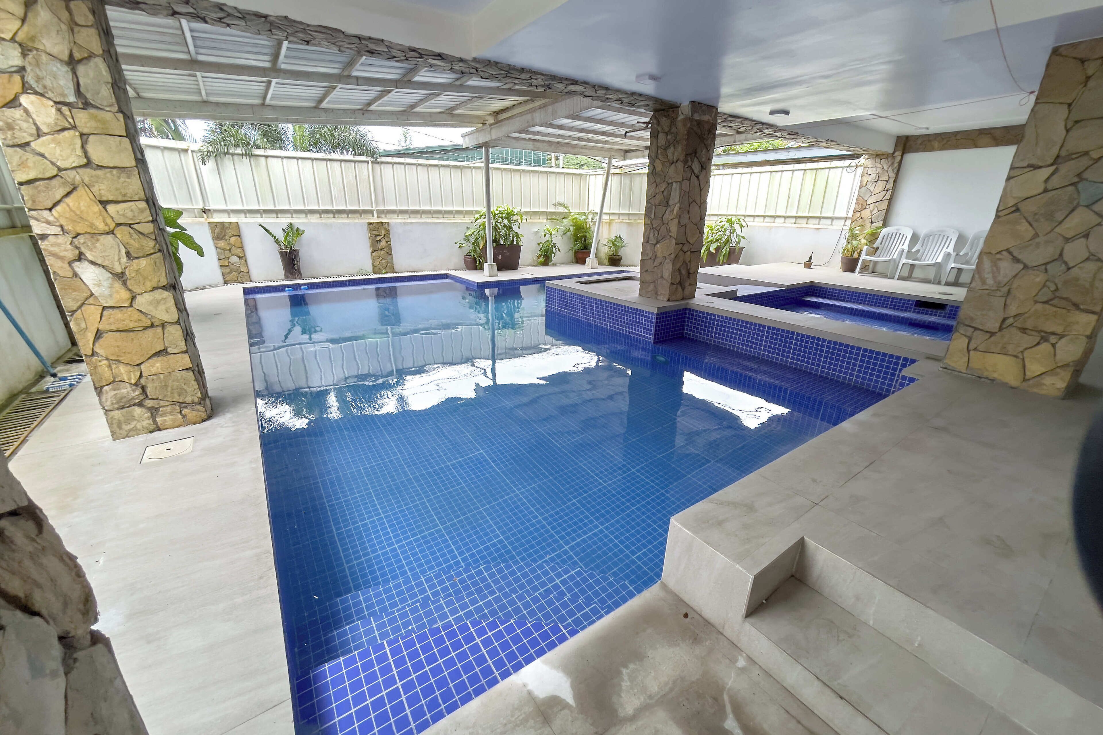 Une piscine avec des piliers en pierre et des marches recouvertes de carreaux.