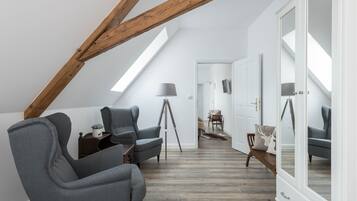 Un dormitorio tipo loft moderno con vigas de madera a la vista, tragaluces, un amplio armario y una zona de estar acogedora con una lámpara.