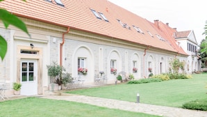 A building with a red-tiled roof, stone walls, and a well-maintained lawn. - Na Kmíně (Obríství)