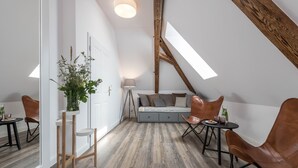 A loft bedroom with a sloped ceiling, a bed, a desk, and a dining area. - Na Kmíně (Obríství)