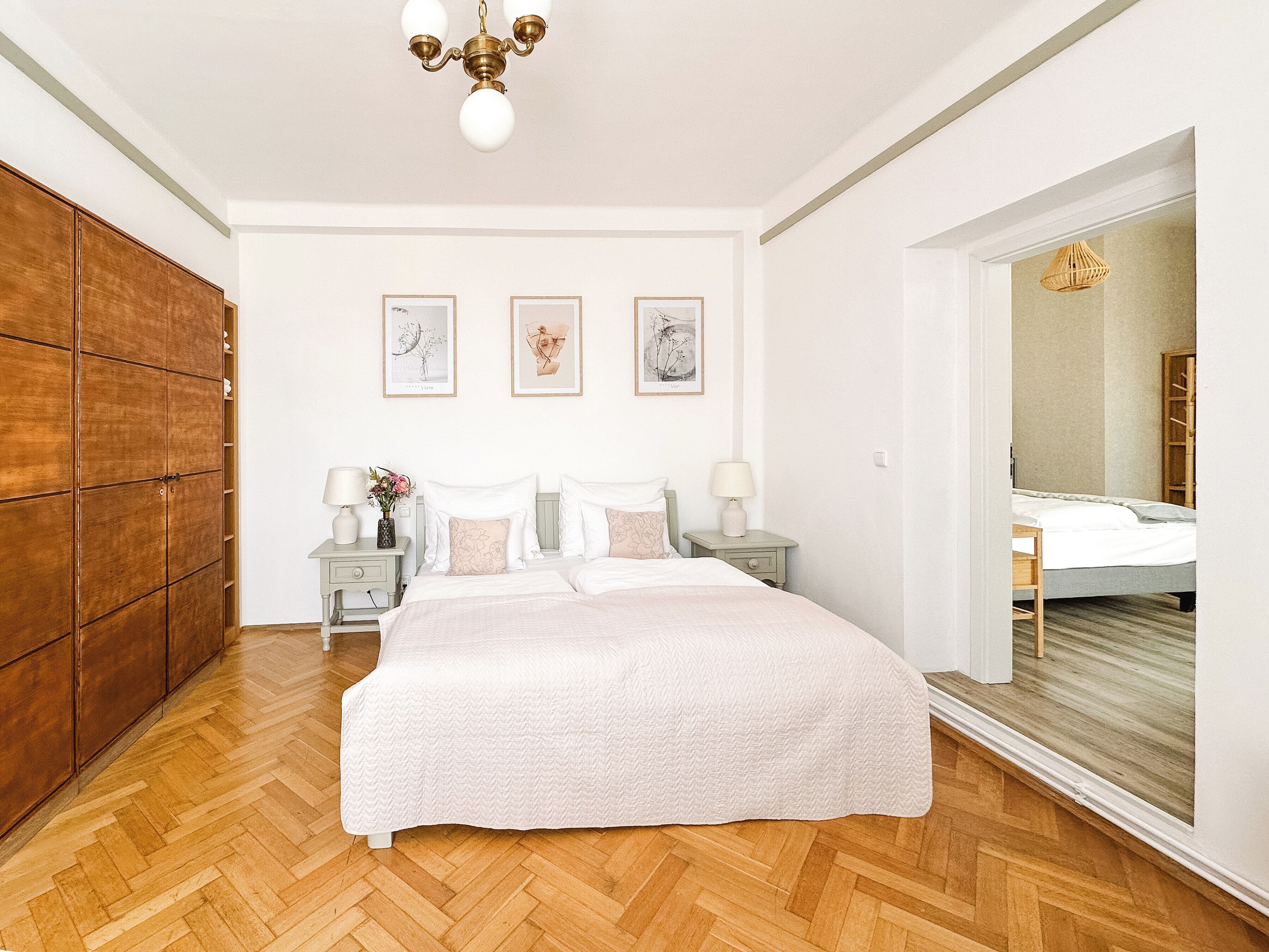 Un dormitorio con una cama grande, dos mesitas de noche, un armario de madera y un espejo.