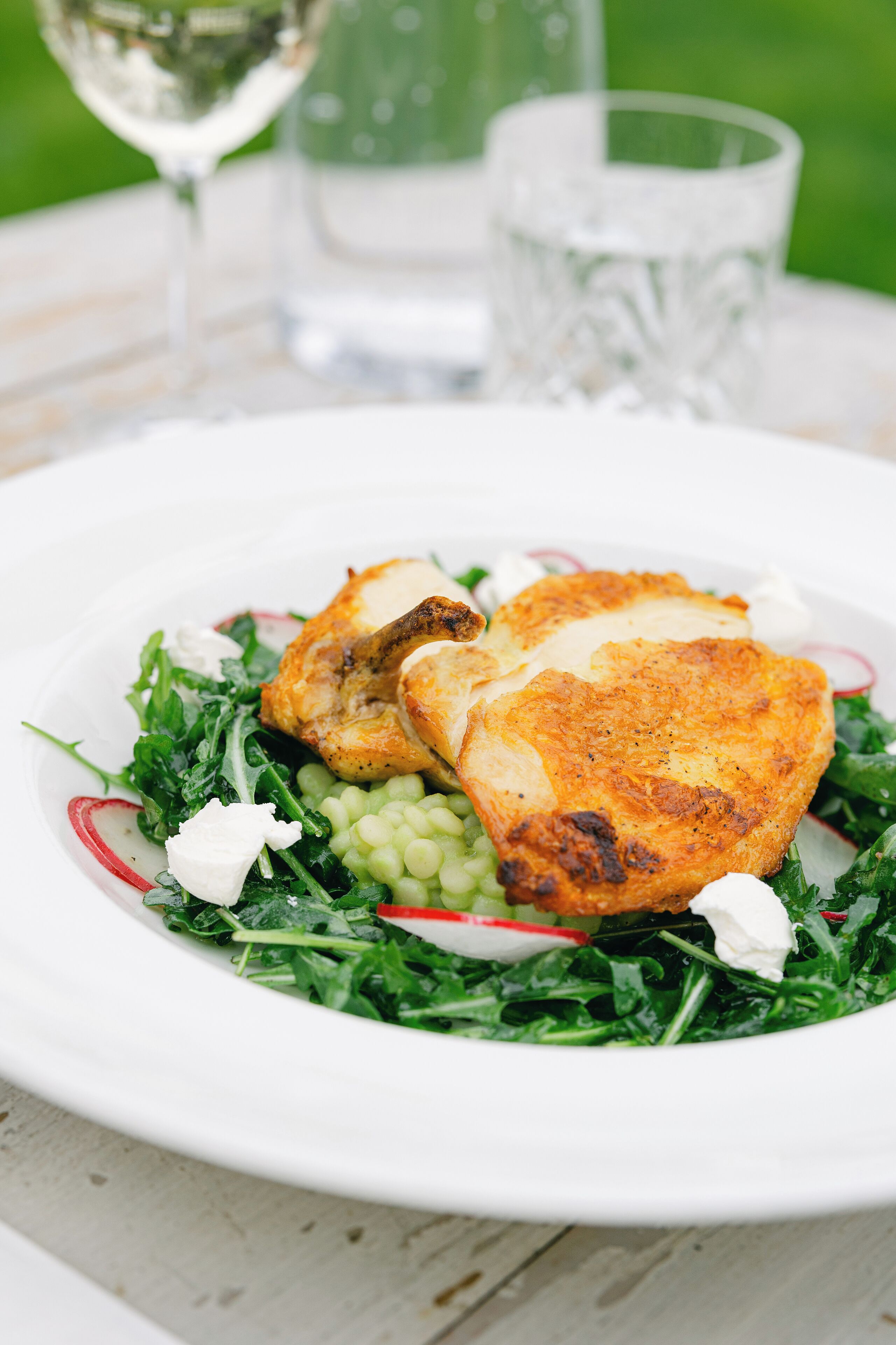 A plate of food with greens, radishes, and a white sauce.