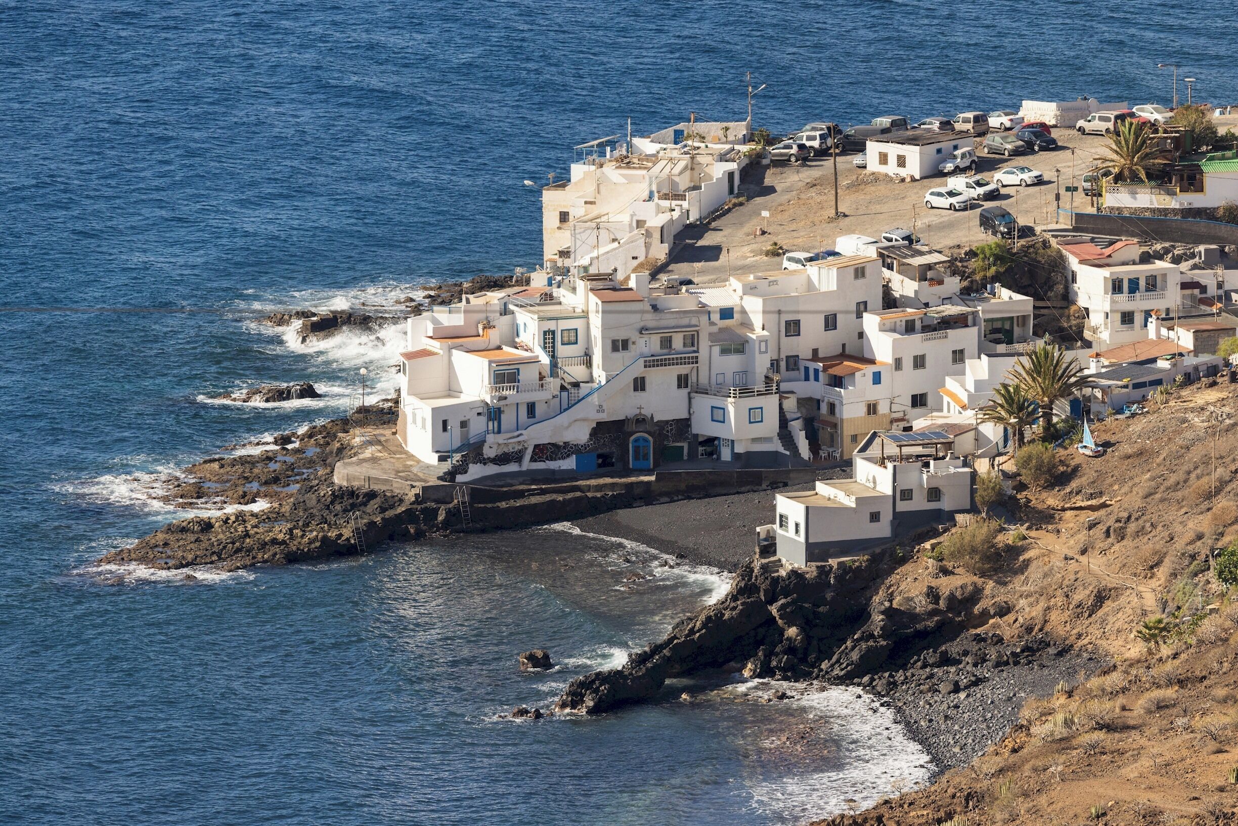 Un villaggio costiero con edifici bianchi, un litorale roccioso e una vista limpida sul mare.