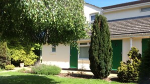 A house with a green door, a small window, and a well-maintained lawn. - Briarsfield Motel (Cheltenham)
