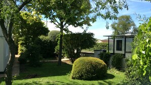 A well-maintained garden with a neatly trimmed hedge, a variety of trees, and a clear sky. - Briarsfield Motel (Cheltenham)