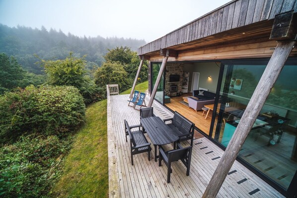 Una casa moderna con terraza que da a un área boscosa.