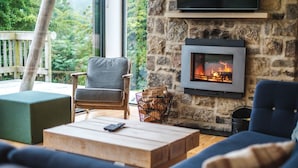 A cozy living room with a stone fireplace, comfortable seating, and a view of greenery outside. - A yorkshire dale that sleeps 6 guests  in 3 bedrooms (Richmond)