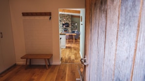 A hallway with a wooden bench, a stone fireplace, and a kitchen area with a wooden floor. - A yorkshire dale that sleeps 6 guests  in 3 bedrooms (Richmond)