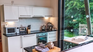 A modern kitchen with white cabinets, a black countertop, a built-in oven, a microwave, and a sink. - A yorkshire dale that sleeps 6 guests  in 3 bedrooms (Richmond)