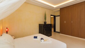 Una habitación de hotel con cama, mesita de noche, lámpara, planta en maceta y armario.