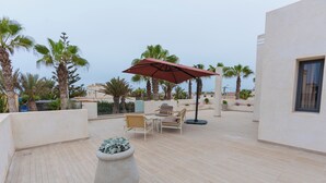 Un patio al aire libre con un conjunto de asientos, un parasol grande y una planta en maceta.