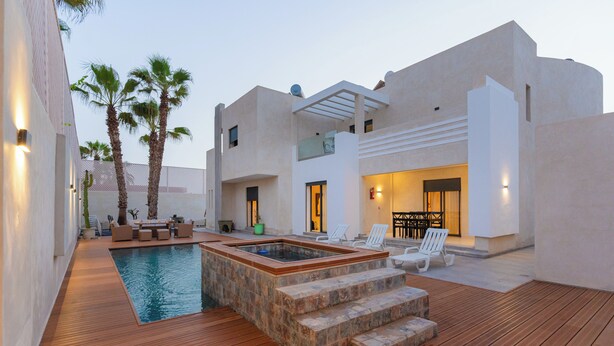 Un área de piscina exterior moderna con jacuzzi, terraza de madera y mobiliario exterior.