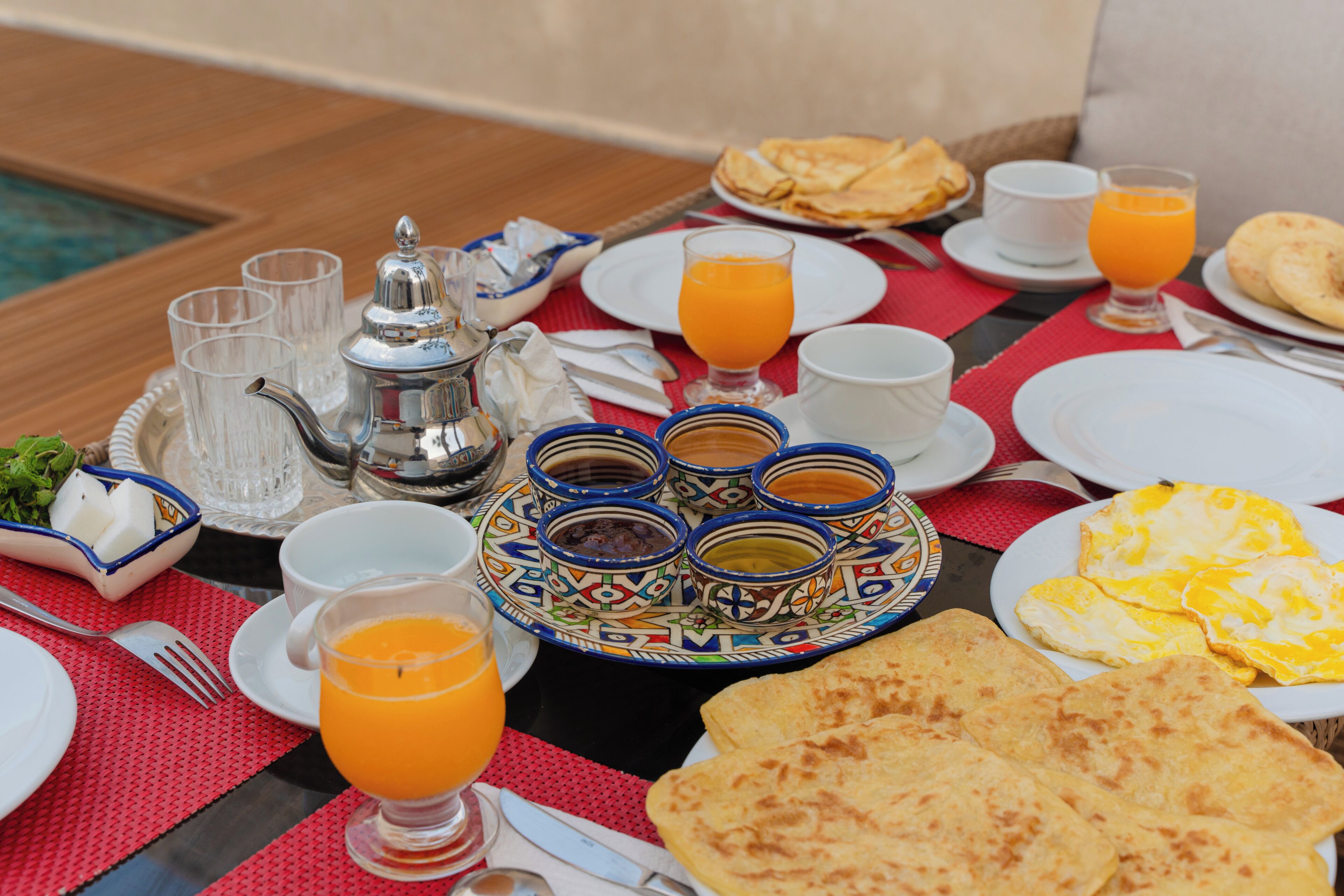 Un desayuno con diversas opciones, como panes planos, huevos y zumo de naranja.