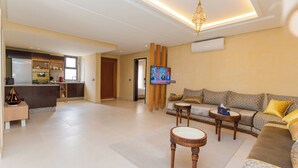 Un amplio salón con un conjunto de sofás, una mesa de centro y un televisor montado en la pared.