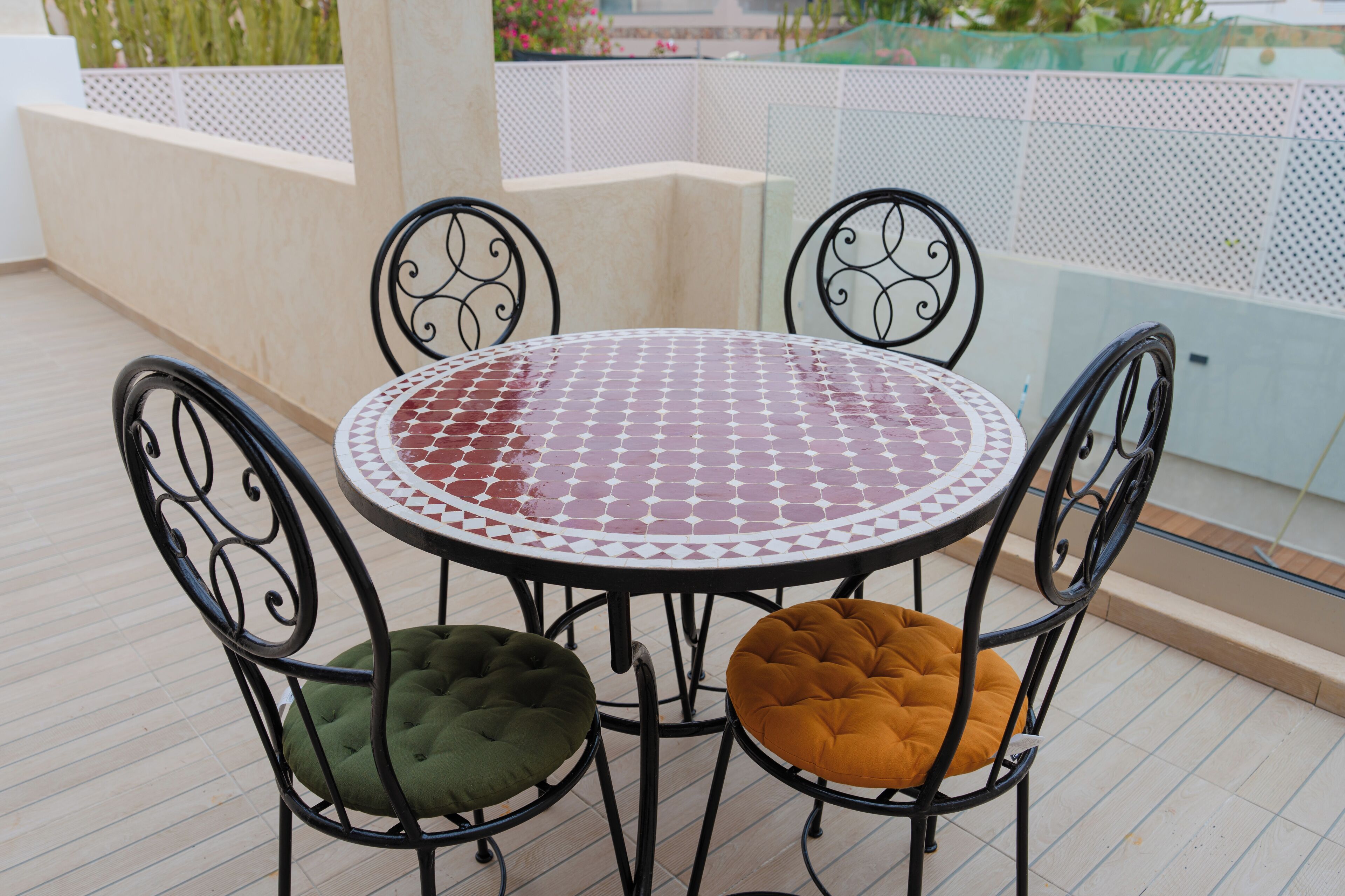 A round table with a patterned tablecloth, surrounded by four chairs with cushioned seats.