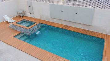 Une piscine rectangulaire entourée d’une terrasse en bois.