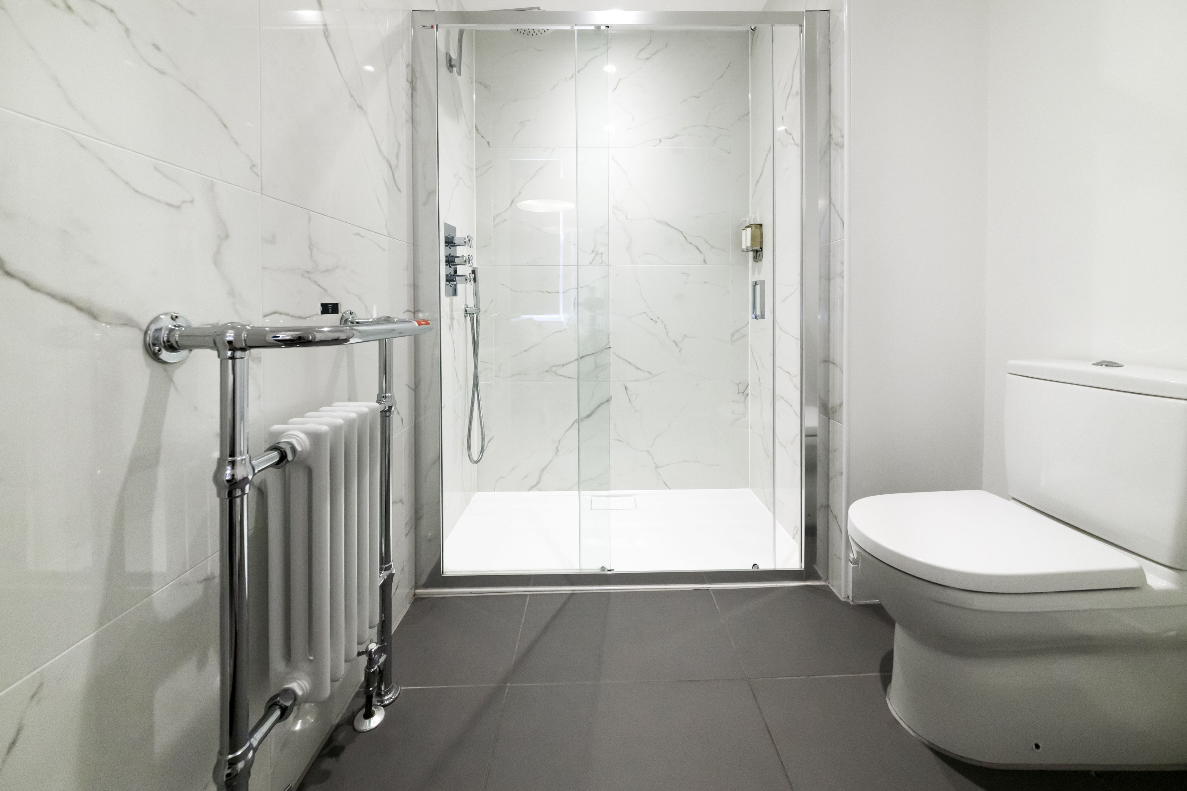 Une salle de bain moderne avec une douche à parois de verre, des toilettes et un radiateur.