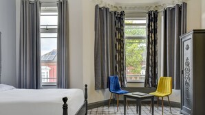 A hotel room with a bed, two chairs, a table, and a cabinet. - Empire Hotel (Leicester)