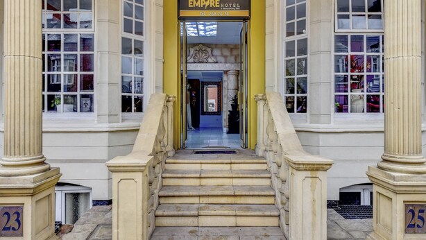 Une grande entrée avec un escalier menant à un hôtel appelé « EMPIRE HOTEL & Salle de réception ».