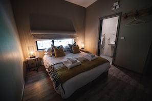 A bedroom with a large bed, two bedside tables with lamps, a window, and a door leading to a bathroom. - Luxury, en-suite lodge with beautiful meadow views - Yorkshire Dales Lodge 10 (Richmond)