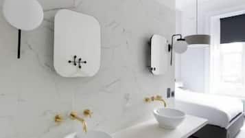 A modern bathroom with a white marble wall, two sinks with gold faucets, a white basin, and a black and white checkered floor.