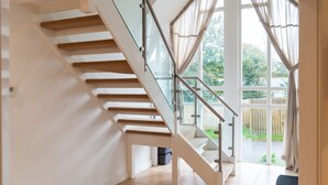 A modern staircase with glass railings and beige carpeted steps leading to a glass door. - Trewhiddle Villa 1 -  a trewhiddle that sleeps 7 guests  in 4 bedrooms (Saint Austell)