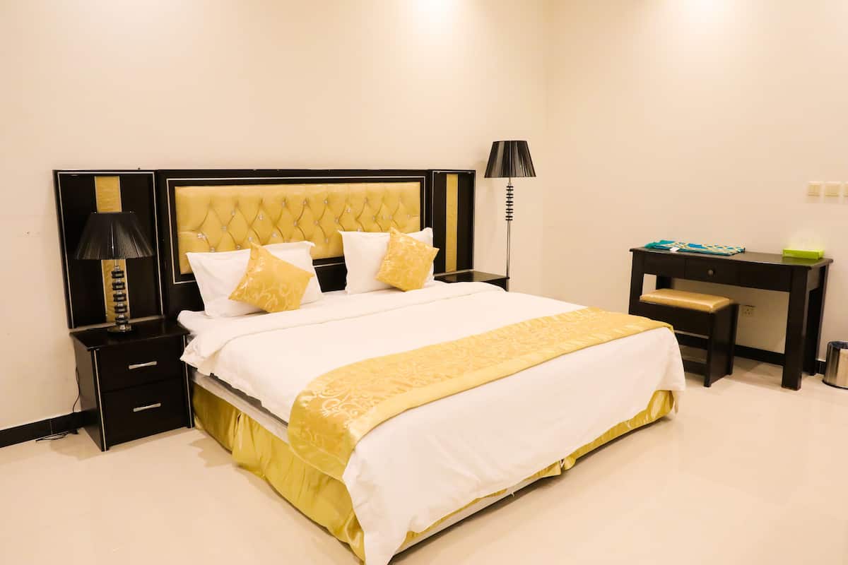 A neatly arranged hotel room with a bed, bedside tables, a desk, and a lamp.