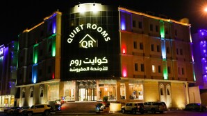 A hotel with a prominent sign reading "QUIET ROOMS" and Arabic text below.