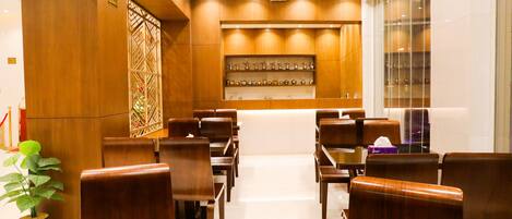 A hotel lobby with wooden furniture, a reception desk, and a wall-mounted display.