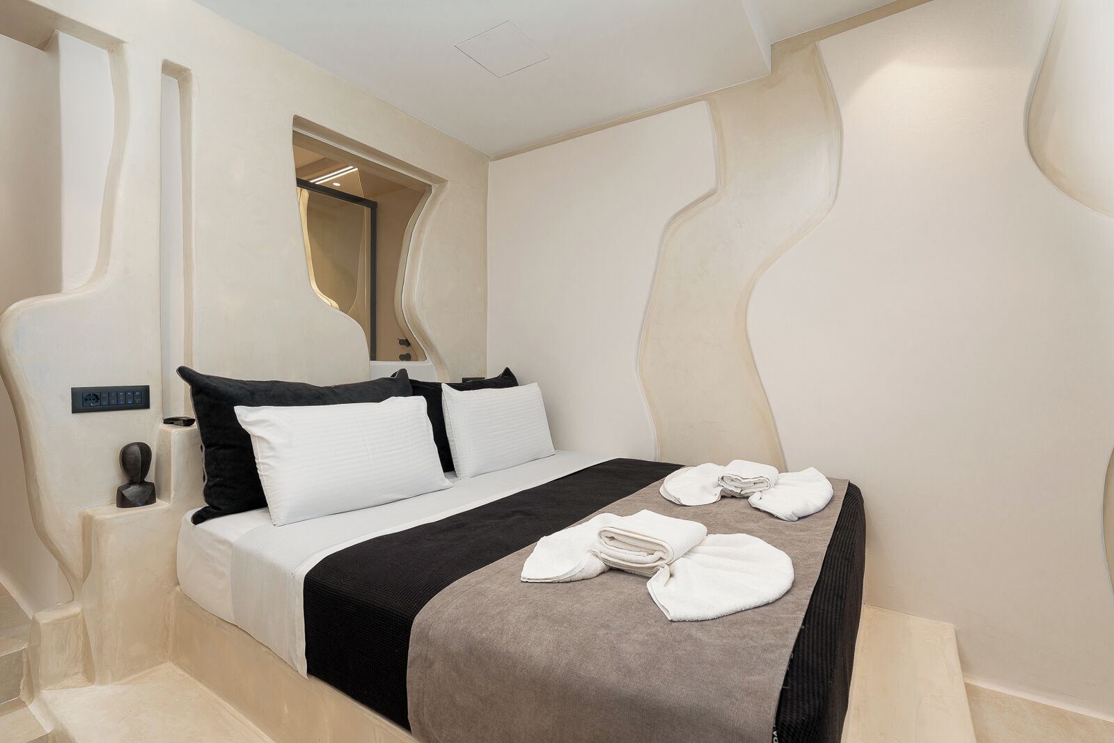 Ein modernes Hotelzimmer mit Bett, Bedienfeld und Handtuchhalter.