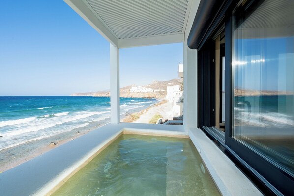 A balcony with a view of the sea and white buildings in the distance.