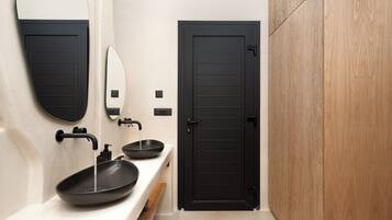 A modern bathroom with a black door, a white sink with a black basin, and a mirror.