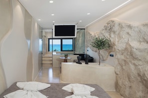 A spa room with a large rock wall, a reception desk, and a view of the sea.