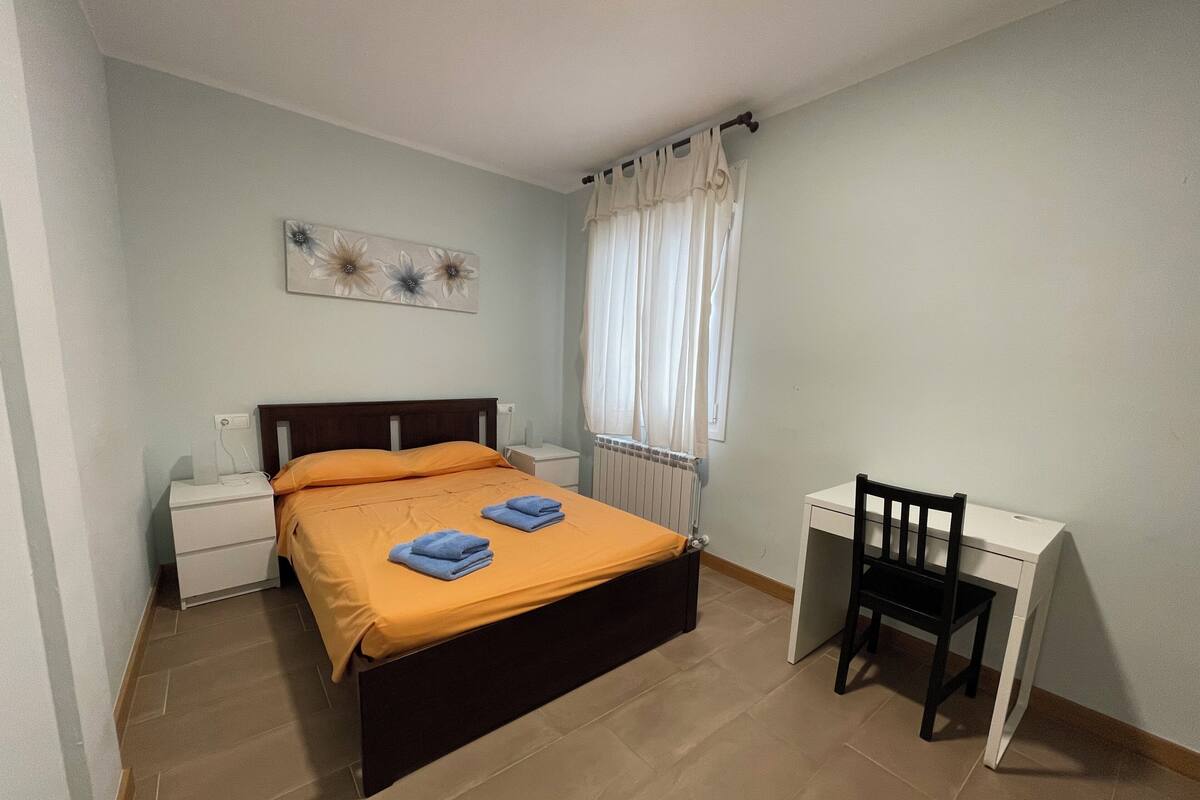 A bedroom with a bed, a desk, and a chair.