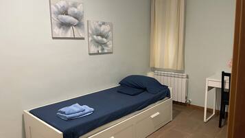 Un dormitorio pequeño y ordenado con una cama individual, una mesita de noche y dos cuadros de flores colgados en la pared.