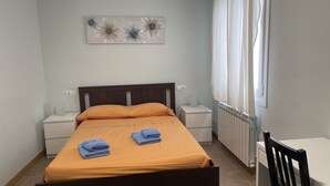 A bedroom with a bed, two nightstands, a radiator, and a window with curtains. - La Encina Azul Rooms (Ponferrada)