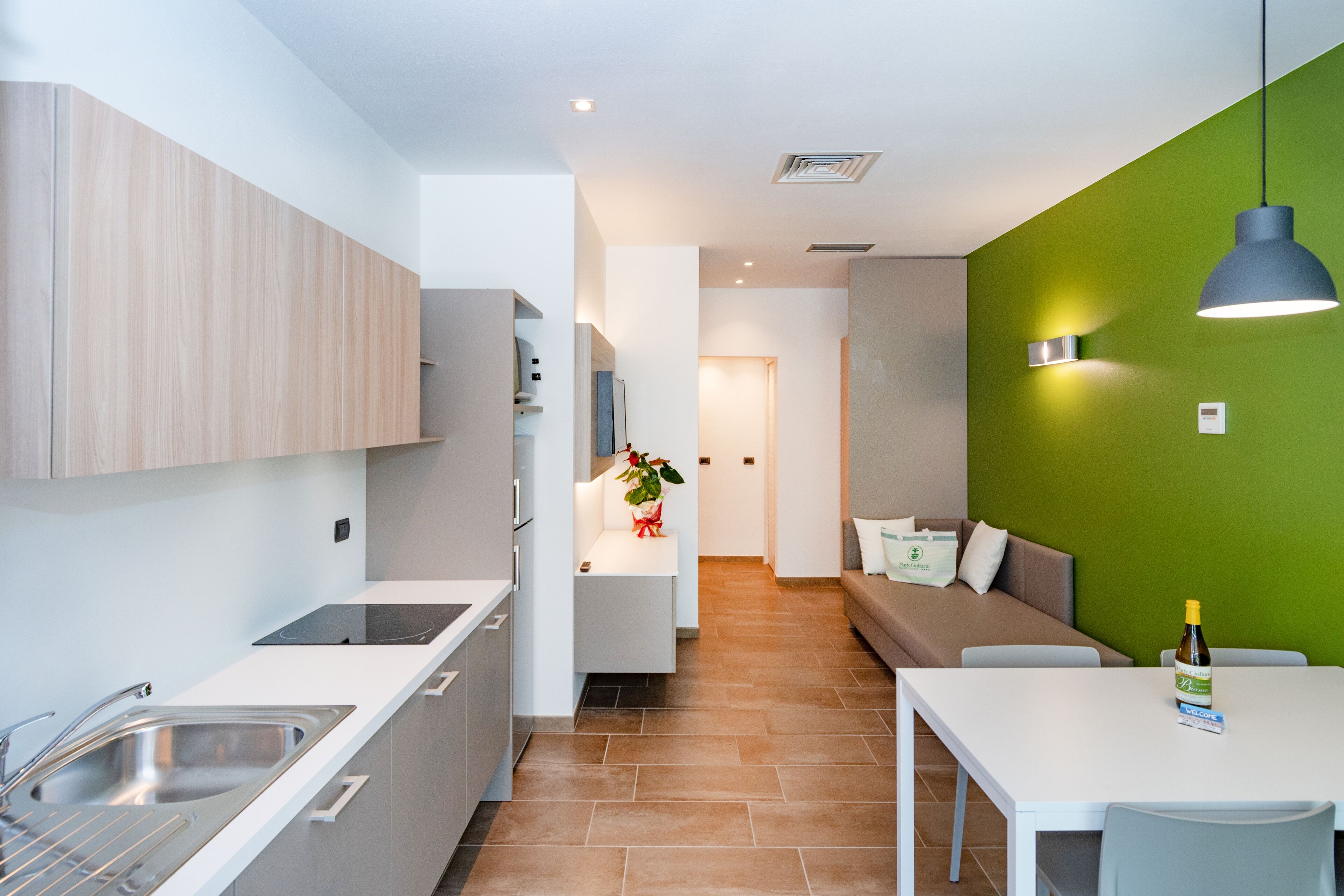 A modern kitchen with a built-in oven, a sink, and a dining area with a table and chairs.