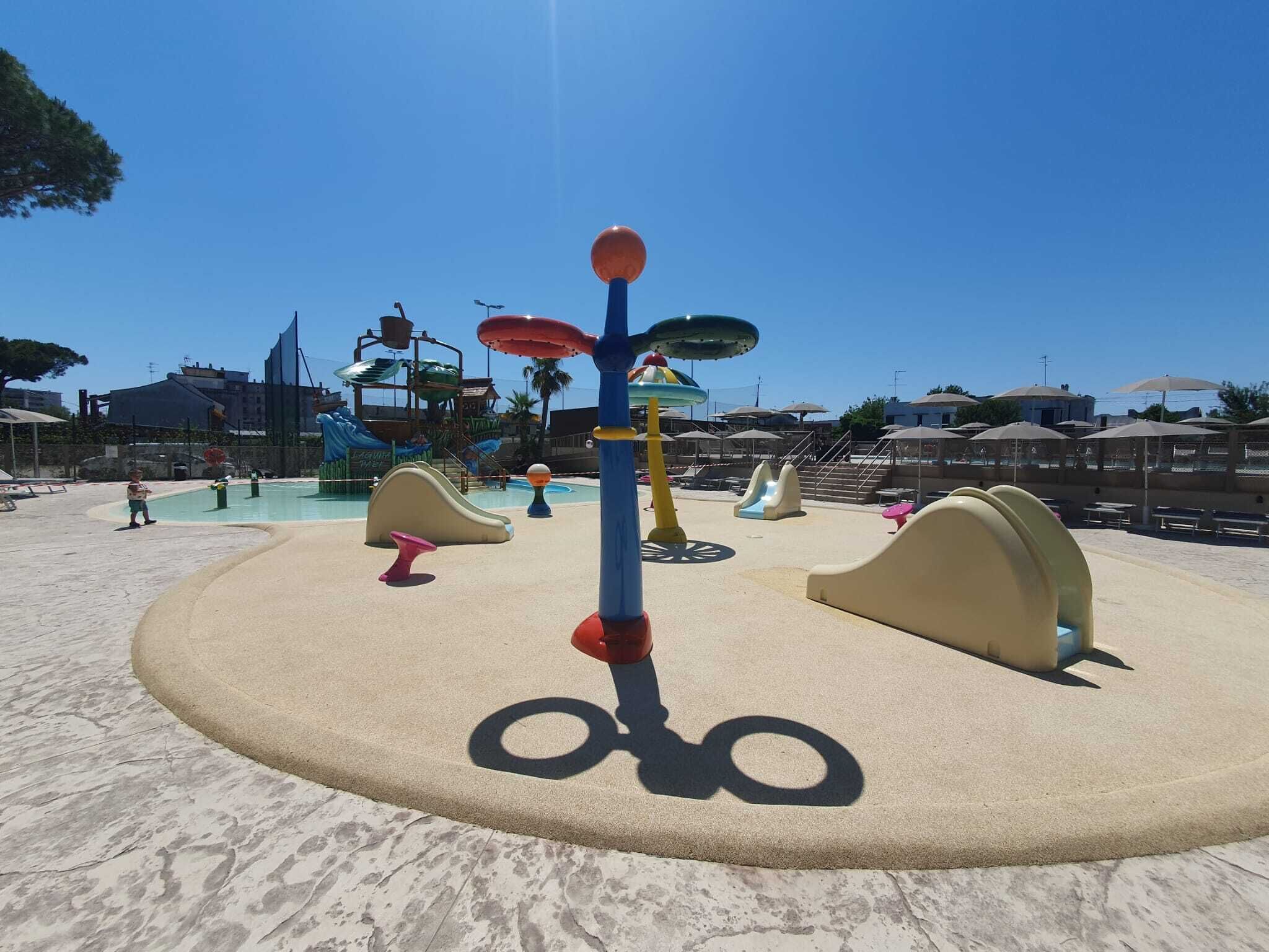 A sandy play area with a central pole and surrounding play structures.