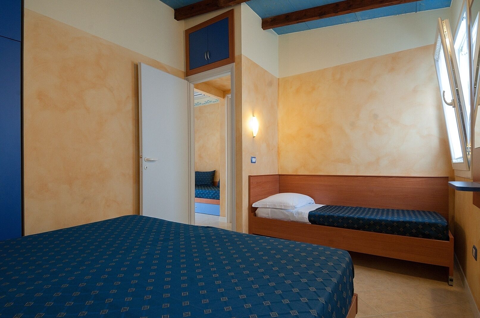 Ein Schlafzimmer mit einem großen Bett, einem kleineren Bett, einem Kleiderschrank und einem Fenster mit Blick.
